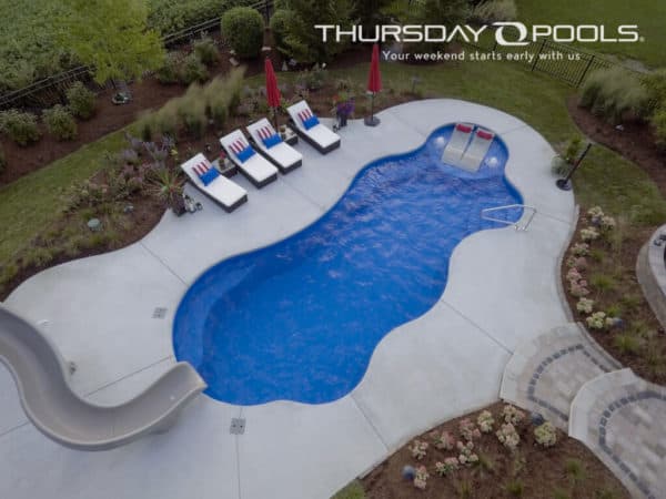 Swimming pool with white pool lounge chairs and pool slide.