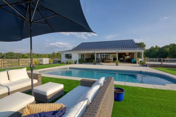 Swimming pool with outdoor seating set and pool cabana in the background.