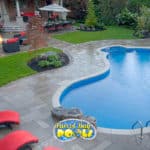 inground fiberglass pool with beautiful landscaping and red patio chairs