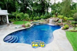 inground fiberglass pool with spillover spa and huge rock formation waterfall