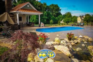 inground fiberglass pool with pool house and nice landscaping