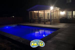 inground fiberglass pool with underwater lights at night
