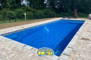 inground fiberglass pool with misiac tile details and paver patio