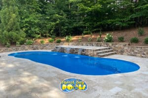 inground fiberglass pool with triple waterfall feature and retaining wall