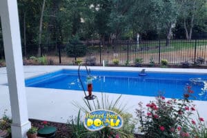 inground fiberglass pool with black safety fencing