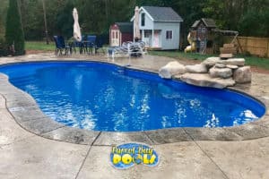 inground fiberglass pool with rock formation and playset
