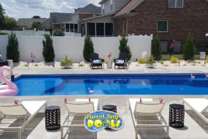inground fiberglass pool with flamingo float and multiple deck chairs