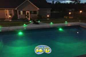 inground fiberglass pool with underwater lights at dusk