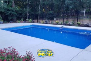 inground fiberglass pool with black safety fencing