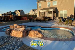 inground fiberglass pool with rock formation water feature