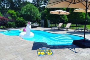 inground fiberglass pool with unicorn float and deck umbrellas