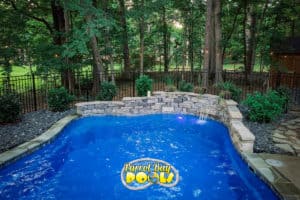 inground fiberglass pool with rock retaining wall and waterfall