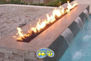 inground fiberglass pool with fire table and waterfalls