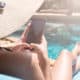 Woman lounging by pool on her phone