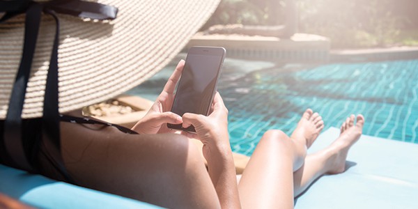 Woman lounging by pool on her phone