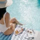Picture of a woman sitting near an inground swimming pool after reading this article about installing a fiberglass pool
