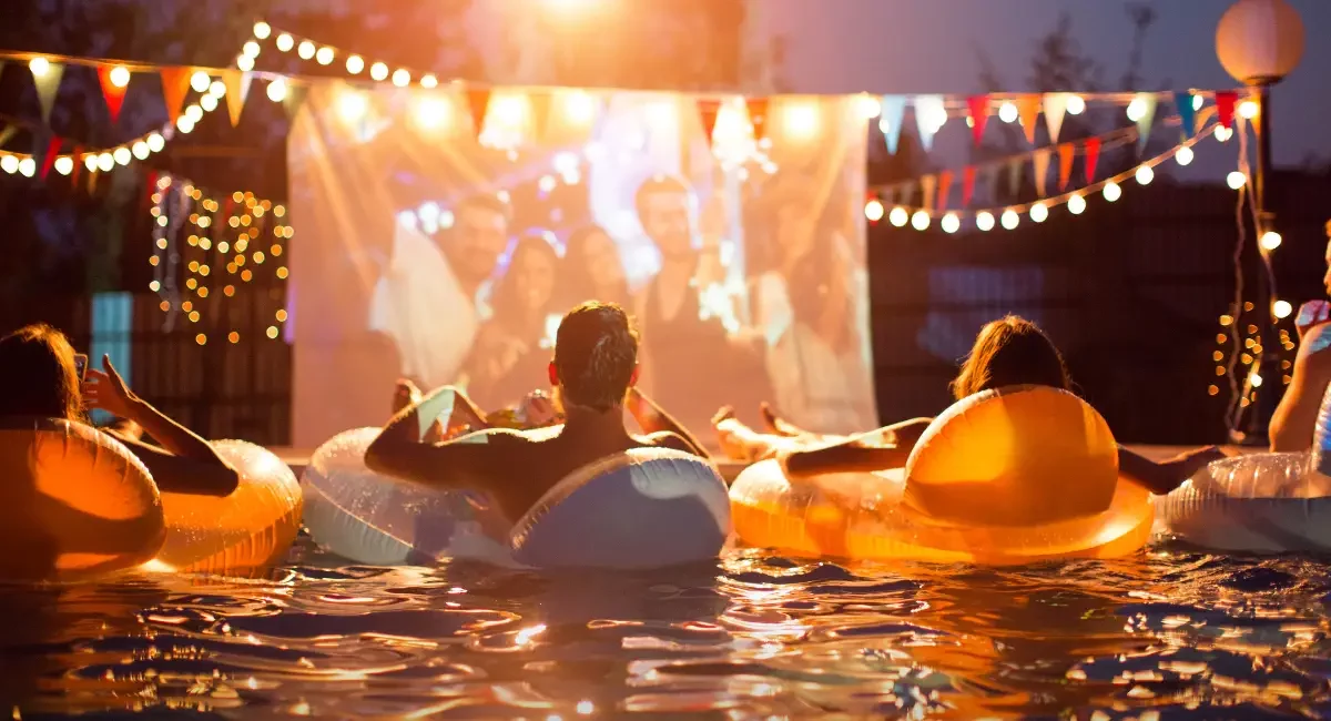 Picture of people watching a movie in a pool after reading the blog about pool party ideas to try.