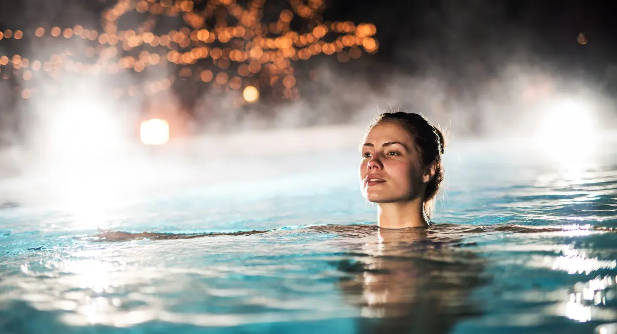 Woman floating in an inground heated pool.