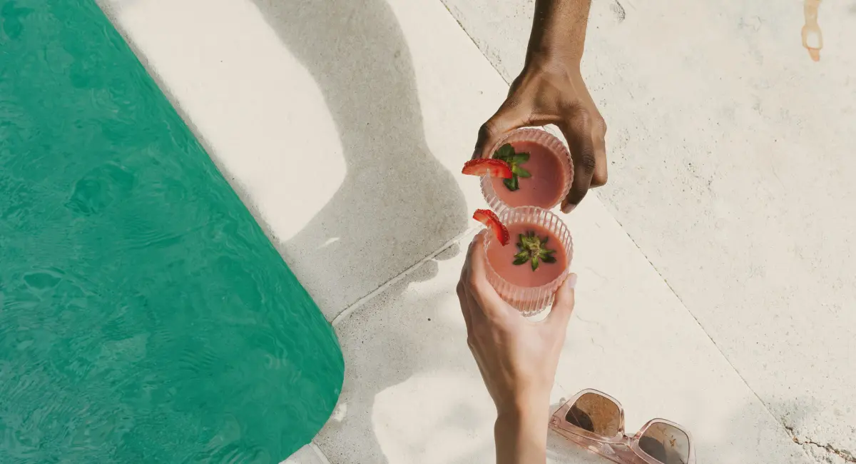 Picture of people holding two cocktails next to a pool for the article about plunge pool vs. cocktail pool in North Carolina.